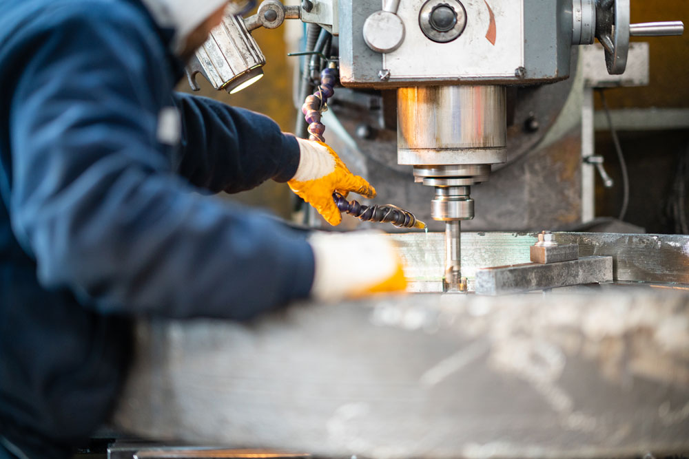 A worker in a factory working on a traditional milling machine.