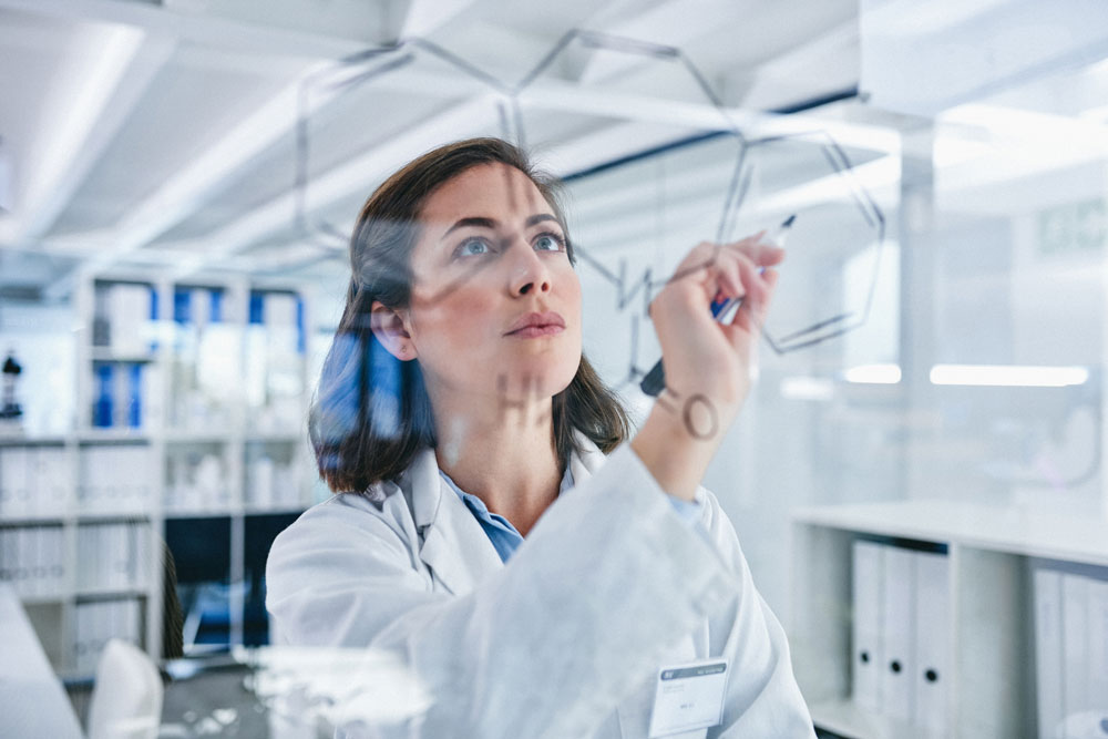 Scientist solving equations on a glass screen in a laboratory.